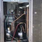 Close-up view of an open HVAC unit showing internal components including copper piping and compressors.
