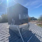 Rooftop HVAC unit installed on a residential property under a clear blue sky.