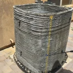 Cleaning a worn-out HVAC condenser coil with a pressure washer on a patio.