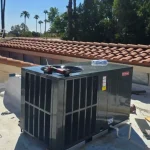 Rooftop HVAC unit installed on a flat surface near a residential tile roof.