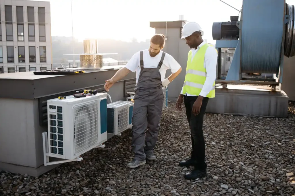  Two HVAC technicians inspecting rooftop air conditioning units.