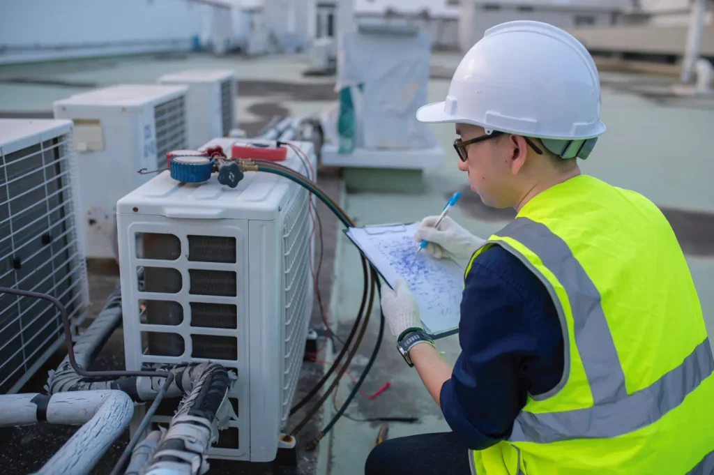 Technician inspecting an air conditioning unit for clogged drain lines.