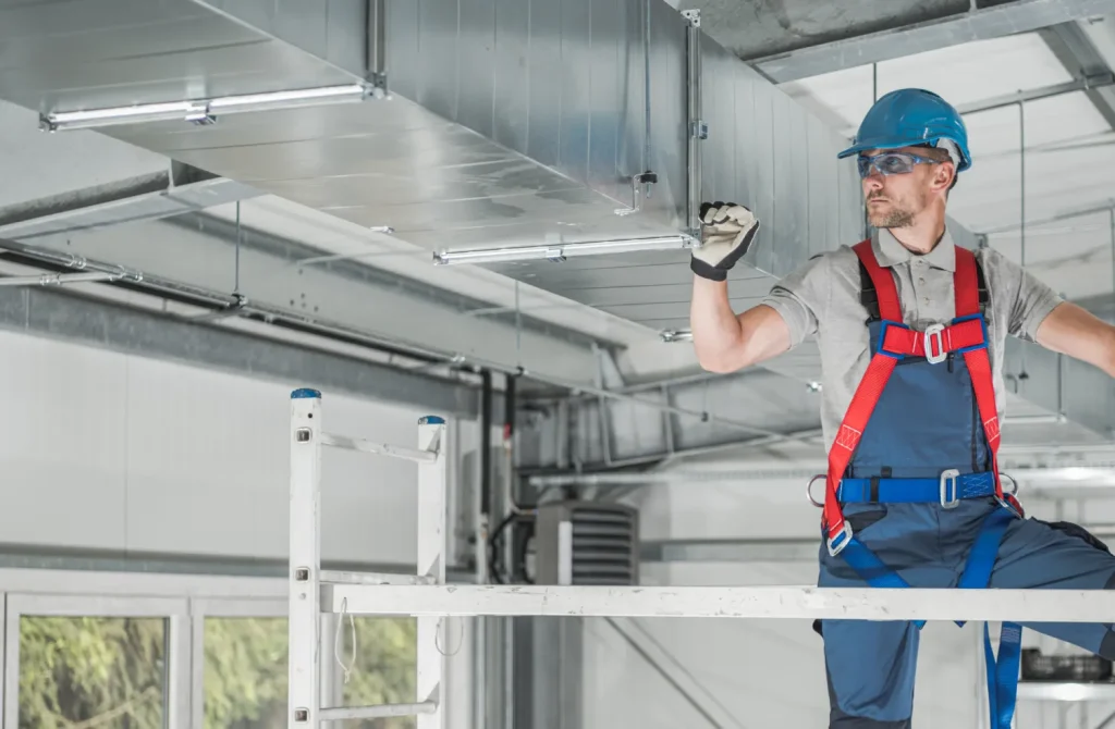 Technician inspecting an HVAC duct system during maintenance.