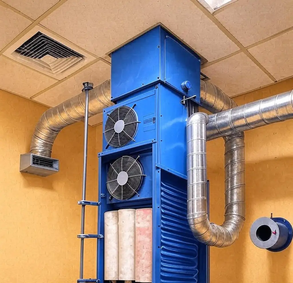 A blue HVAC unit with metal air ducts mounted on a yellow wall and ceiling.